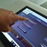 Modern meeting room with cloud-based AV control dashboard on screen representing smart meeting management.