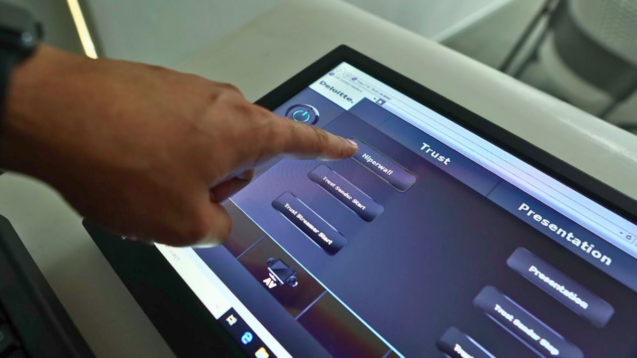Modern meeting room with cloud-based AV control dashboard on screen representing smart meeting management.